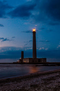 Lighthouse by sea against sky at dusk