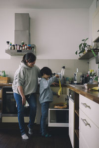 Happy mother looking at daughter putting banana peel in garbage at home