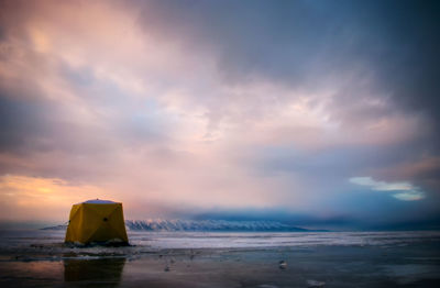 Winter fisher's tent on frozen lake at colourful sunset