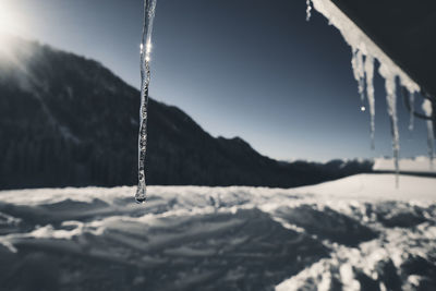 Close-up of icicles on mountain against sky