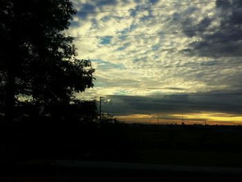 Silhouette trees on landscape against sky at sunset