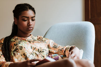 Ethnic woman with book resting at home