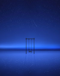 Swing over sea against clear blue sky at night