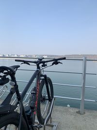 Bicycle by sea against clear blue sky