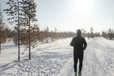 Sporty man in sportswear running in a winter park, copy space. a runner trains outdoors, jogging in