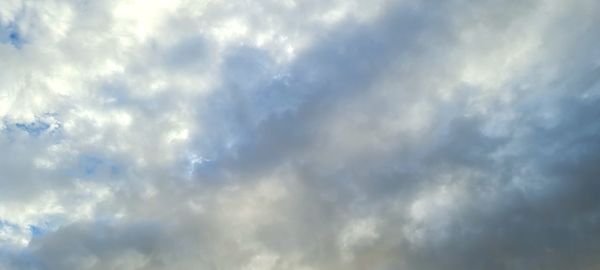 Low angle view of sunlight streaming through clouds