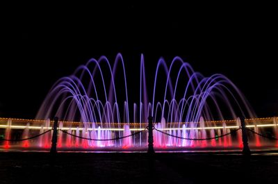 Light trails on bridge against sky at night