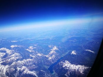 Aerial view of sea and landscape against blue sky