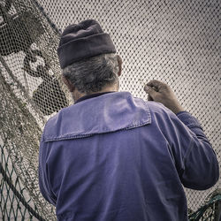 Rear view of man standing by fence