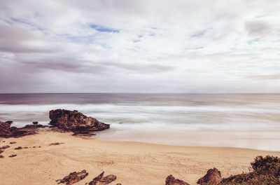 Scenic view of beach against cloudy sky