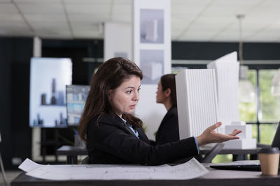 Portrait of young woman using laptop while standing in cafe