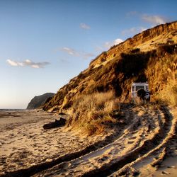 Vehicle on beach against cloudy sky