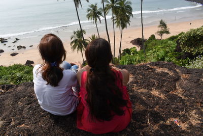 Rear view of women sitting on beach