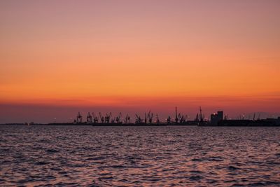 View of harbor against orange sky during sunset