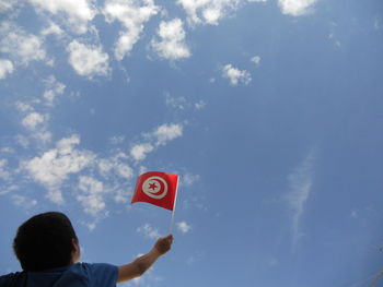 Low angle view of man holding hands against sky