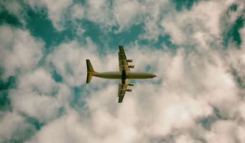 Low angle view of airplane flying against cloudy sky