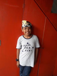 Portrait of smiling boy standing against red wall