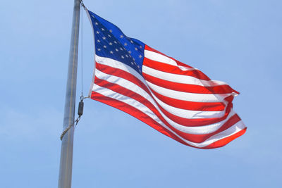 Low angle view of flags against clear blue sky