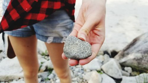 Midsection of woman holding rock at beach