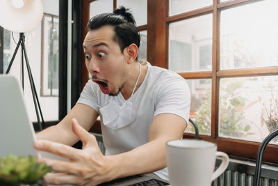 Mid adult man using mobile phone while sitting on table