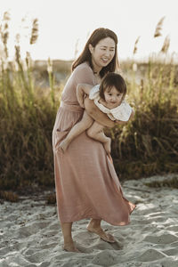 Mid view of mother playing with 2 year old at beach during sunset