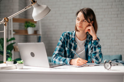 Thoughtful woman looking away while working at office