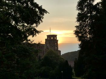 Silhouette trees and buildings against sky during sunset