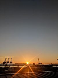 Silhouette shipping yard against sky during sunset