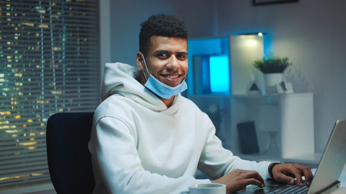 Portrait of young man using laptop at home