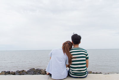 Rear view of couple on beach against sky