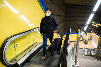 Blind man walking on escalator with guide dog