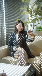 Young woman sitting on sofa at home