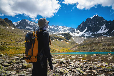 Woman on a mountain with a backpack is watching a beautiful view of the mountains in the background