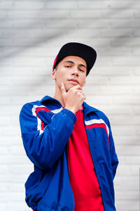 Portrait of young man standing against wall