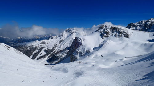 Scenic view of snow covered mountains against blue sky