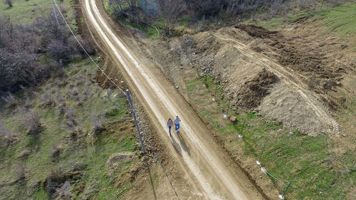 Aerial view of man and woman walking on dirt road