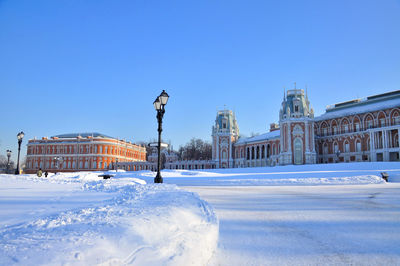 Snow covered street by buildings against sky