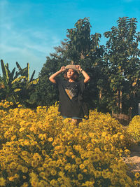 Woman standing by yellow flowering plants