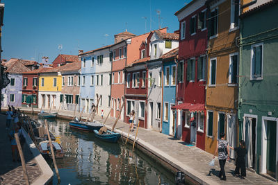 Buildings by canal in city against sky