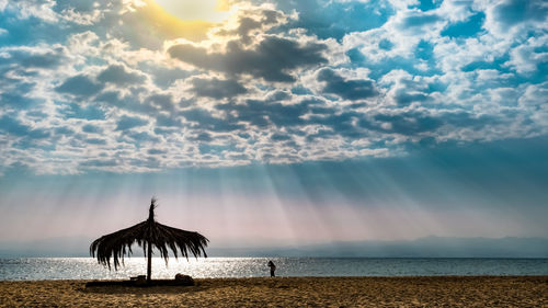 Silhouette beach against sky during sunset