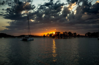 Sailboats in sea against sky during sunset