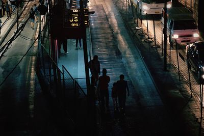 People walking on illuminated road in city