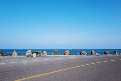 Long empty road along calm blue sea