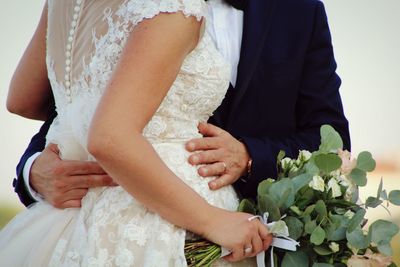 Midsection of couple holding bouquet