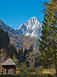 House amidst trees and mountains against clear sky