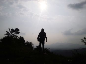 Silhouette man on mountain against sky