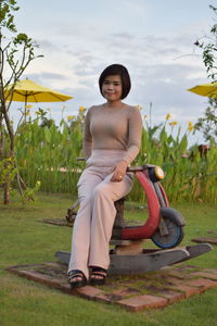 Portrait of smiling woman sitting on land against sky