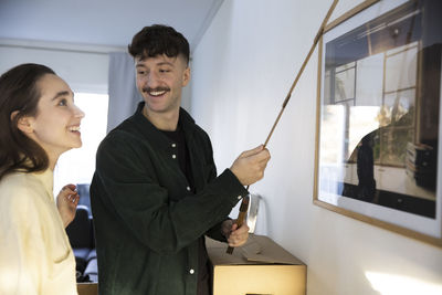 Happy young couple with tape measure standing in new house