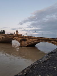 Arch bridge over river against sky