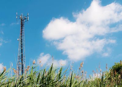 Low angle view of communications tower against cloudy sky during sunny day